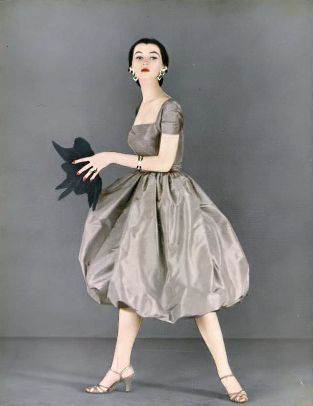 Dovima in bouffant silk taffeta skirt with separate square-cut taffeta top by Mollie Parnis, Coro earrings, Hattie Carnegie fan, Harper's Bazaar, February 1951