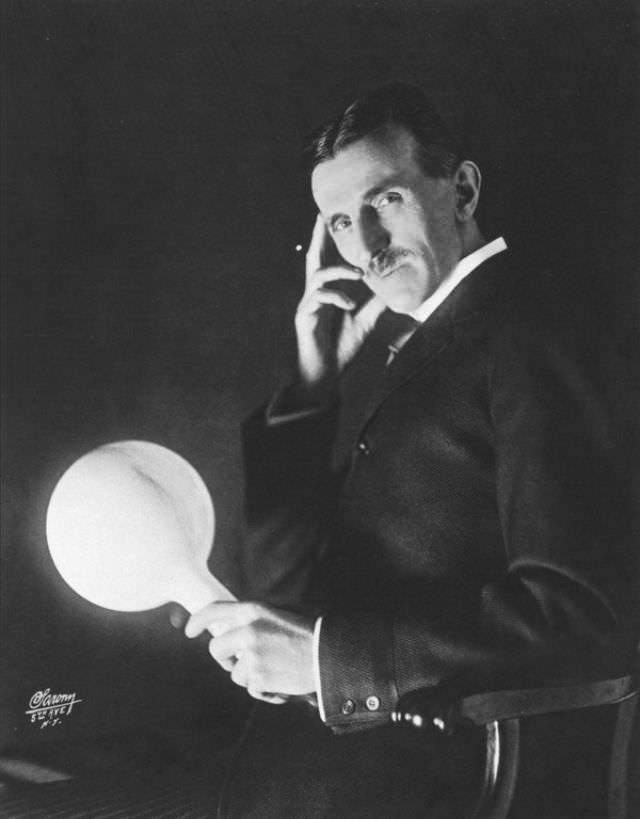 Tesla holding a gas-filled phosphor coated wireless light bulb which he developed in the 1890’s, half a century before fluorescent lamps come into use. Published on the cover of the Electrical Experimenter in 1919.