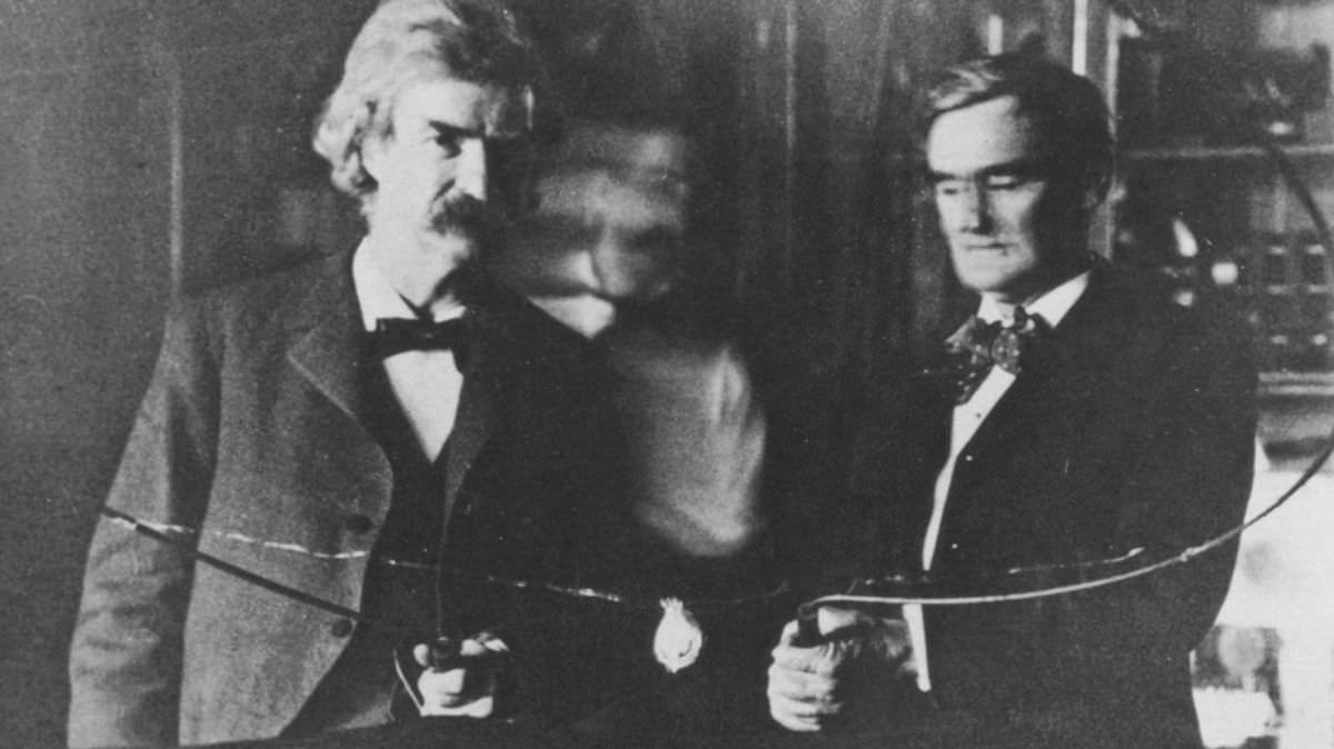 Nikola Tesla (blurred at center) performs an electrical experiment for writer Samuel Clemens (left), aka Mark Twain, and actor Joseph Jefferson in 1894.