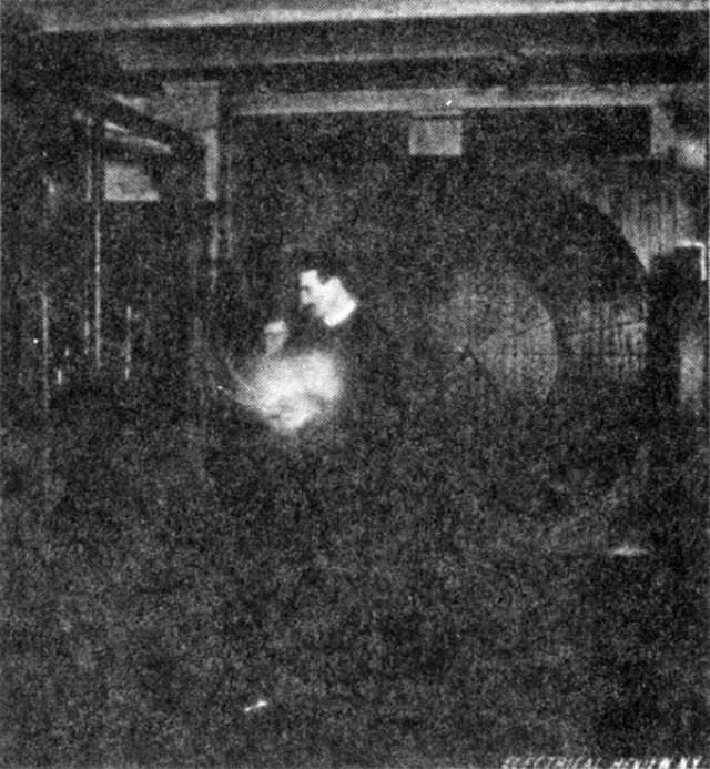 Photograph of the experimenter standing in the middle of the laboratory and lighting a vacuum bulb by waves from a distant oscillator — His body is, in this case, subjected to great electrical pressure.