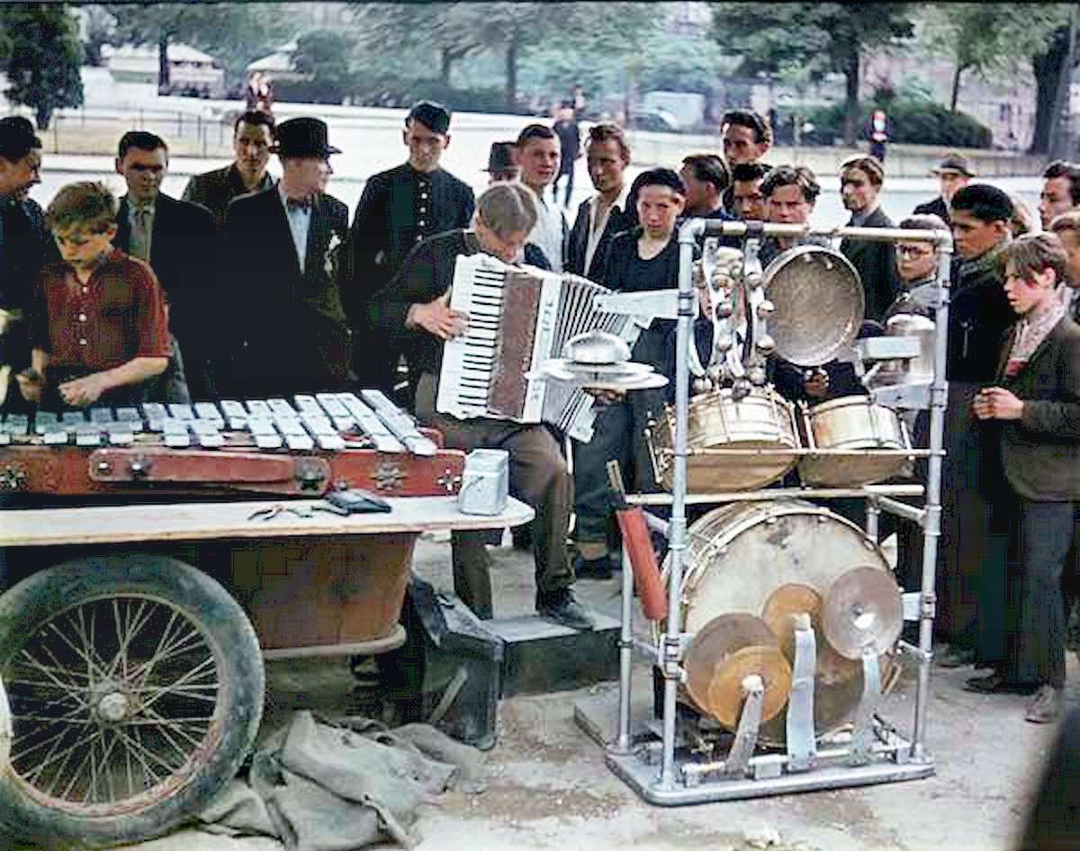 A crowd surrounds a traveling band as they play music in a Paris street.