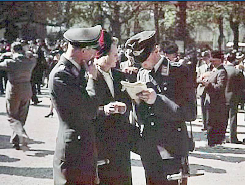 Officers from the Wehrmacht chat with a Parisian woman.