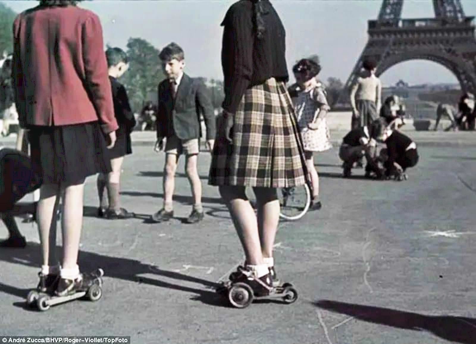 Girls and boys play in what appear to be the early forerunners of rollerskates against the backdrop of the Eiffel Tower on central Paris’s Champ de Mars.