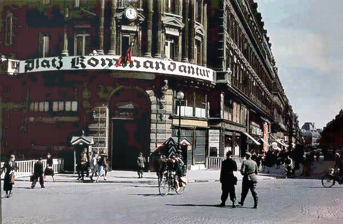 Guard posts stand outside a building the sign of which advertises it as an important spot for the occupying German army.