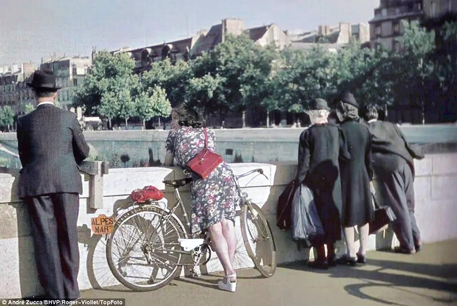 A shapely woman leaning over the side of the bridge is the focus of this photograph.