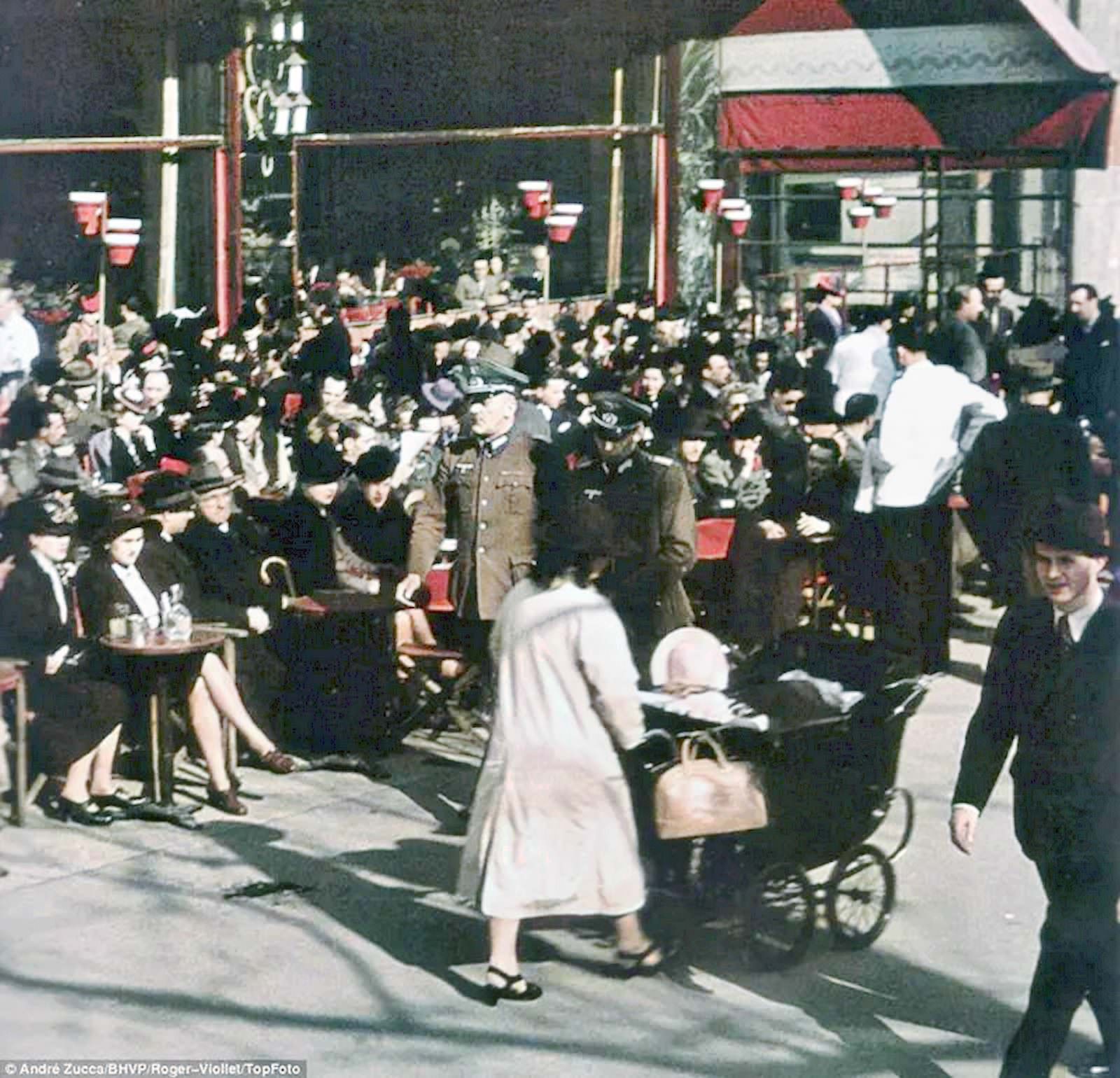 Senior-looking German army officers stroll past a crowd of French enjoying the afternoon in one of Paris’s outdoor cafés.