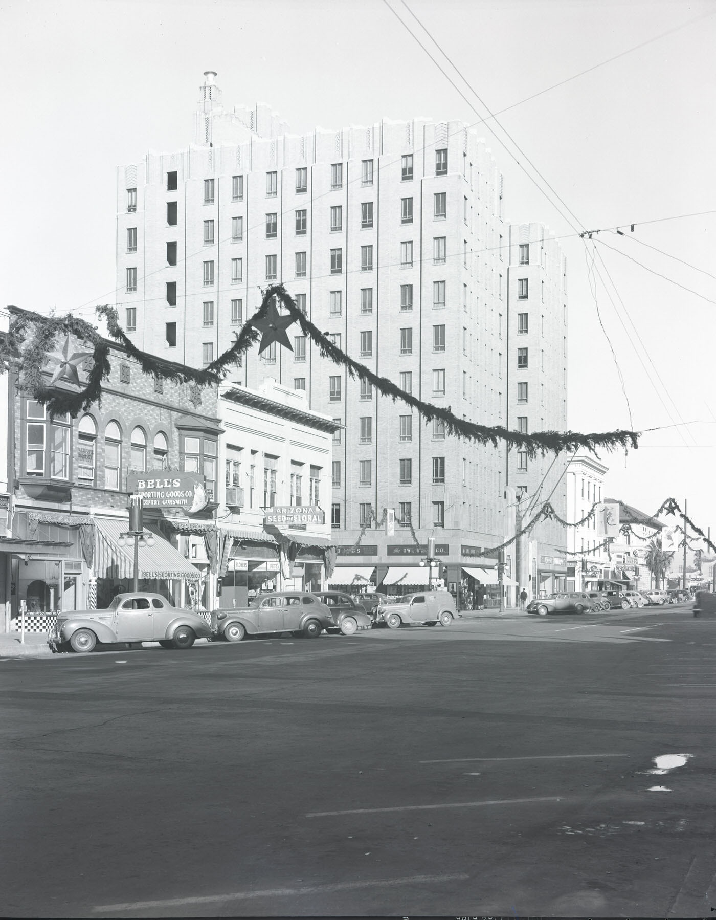 1st Avenue. Depicts the 40 block of N. 1st Ave. Visible are Bell's Sporting Goods (40 N. 1st), New Arizona Seed & Floral Co. (46 N. 1st), and Christmas decorations, 1941