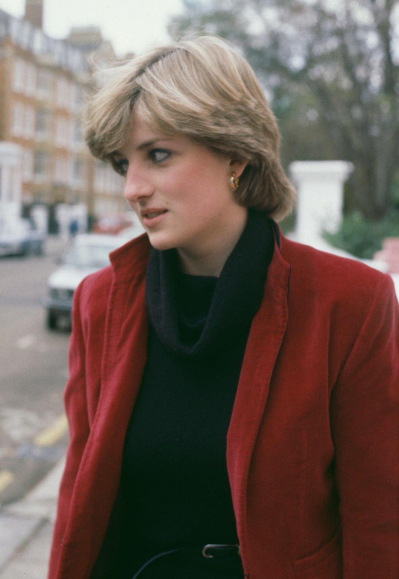 Diana, Princess of Wales, wearing a red jacket over a black sweater, outside her home in Earl's Court, London, 1980