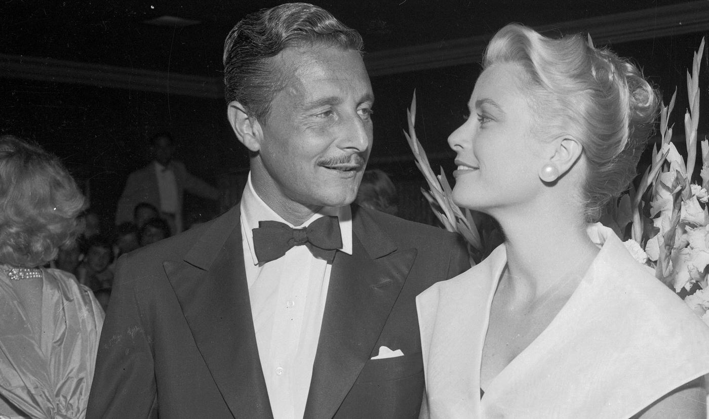 Grace Kelly Chats with Oleg Cassiniin the lobby of a theater during the premiere of Rear Window, Miss Kelly's latest film.