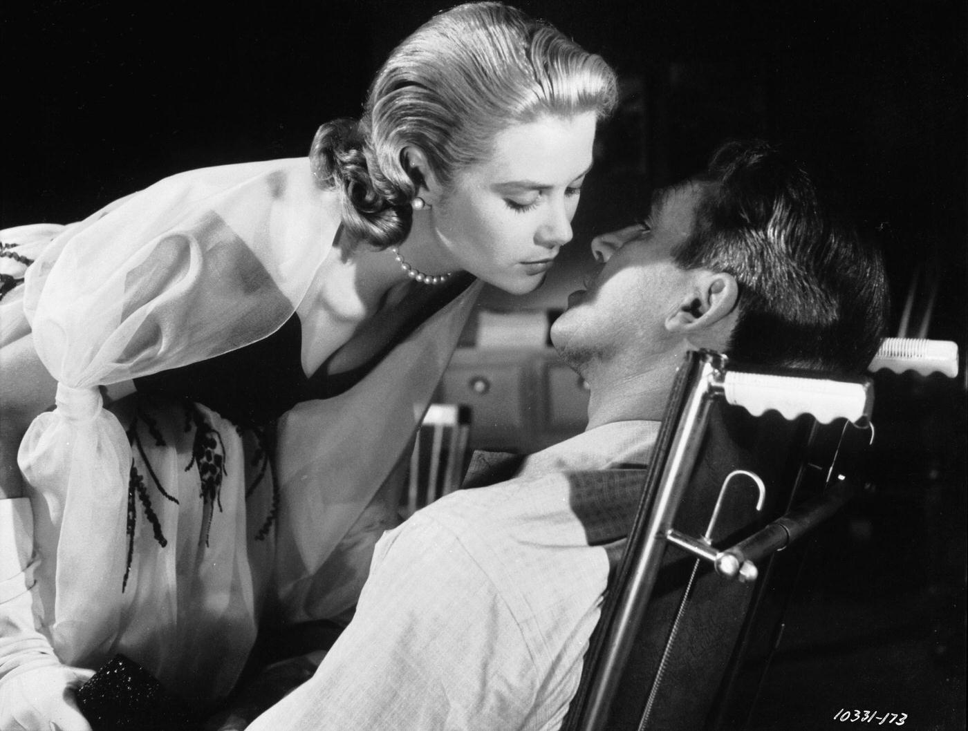 Grace Kelly leans over to kiss James Stewart in a scene from Hitchcock's suspense mystery 'Rear Window'. .