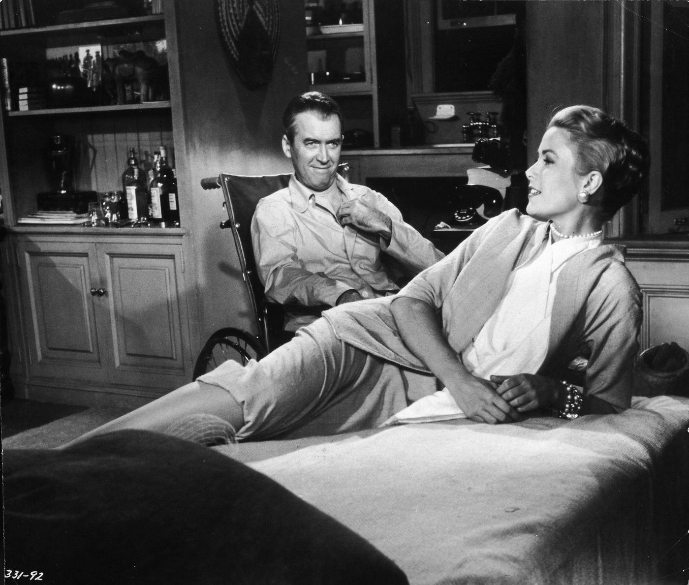 Grace Kelly reclines on a bed while actor James Stewart smiles at her from a wheelchair in 'Rear Window,' 1954.