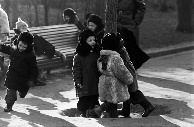 Warmly-dressed children playing in a public garden.