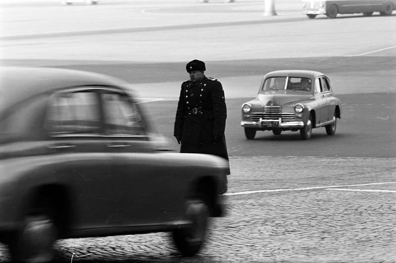 A traffic policeman in the center of a wide cobbled avenue.