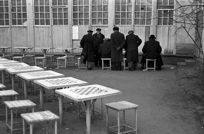 Men playing chess in a courtyard.