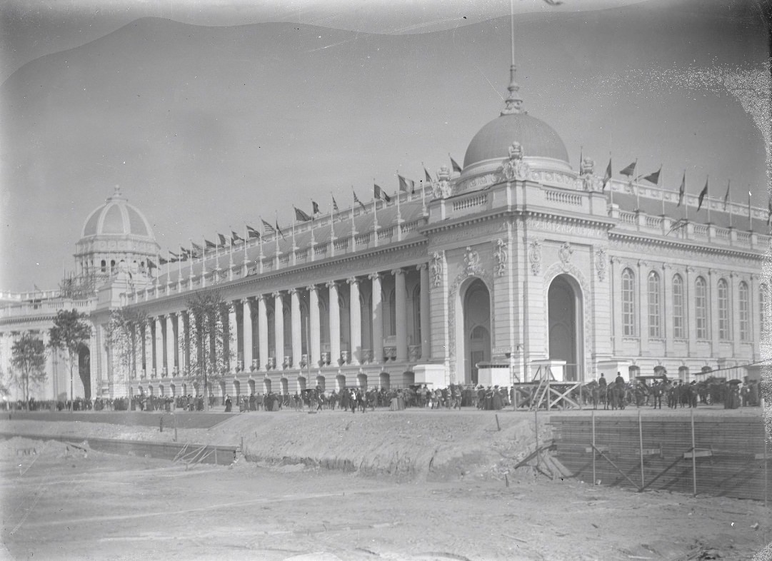 World's Fair building surrounded by a crowd of people. In front of the building is still under construction.