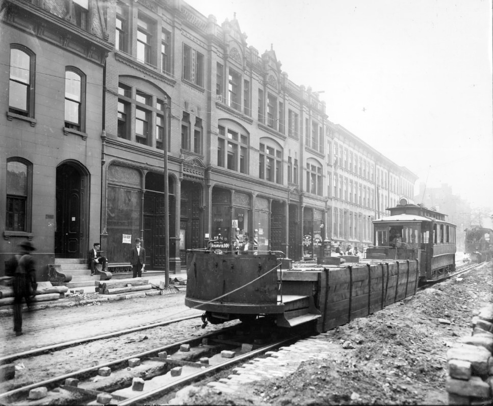 Streetcars on street under repair, a modified streetcar with the cab removed is in the foreground, 1900