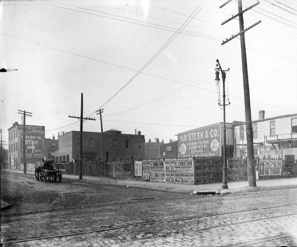 Street intersection with theater posters and building billboards visible, 1900