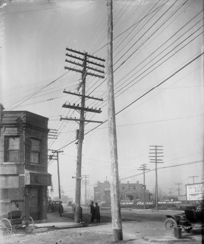 South Taylor Avenue and Manchester Avenue, 1900. A bar is visible at the corner. Two men are in a discussion in the street. An automobile is partially visible on the right.