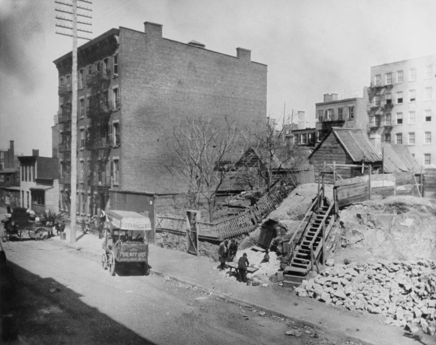 Carts parked along the sidewalk with a small wooden shed atop a mound of earth