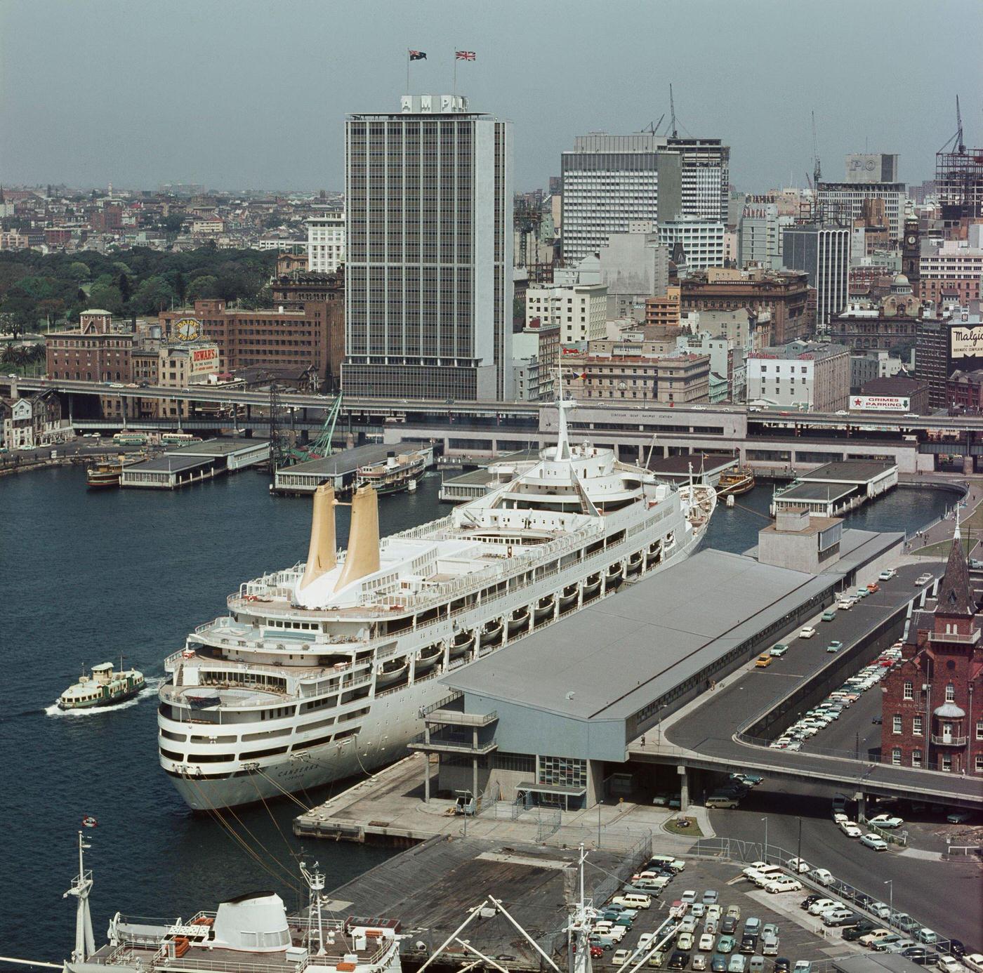 View from Sydney Harbour Bridge of the Circular Quay wharves and Overseas Passenger Terminal underneath the recently completed AMP Building office block in downtown Sydney, 1960s