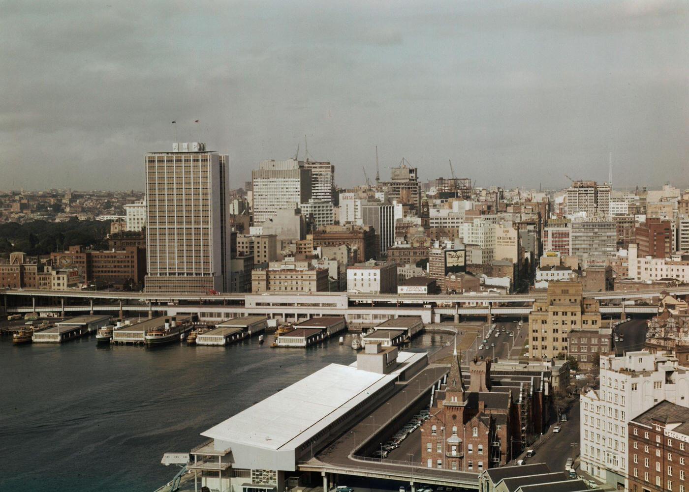 Sydney Harbour Bridge of the Circular Quay wharves and Overseas Passenger Terminal overlooked by the recently completed AMP Building office block in downtown Sydney, 1963