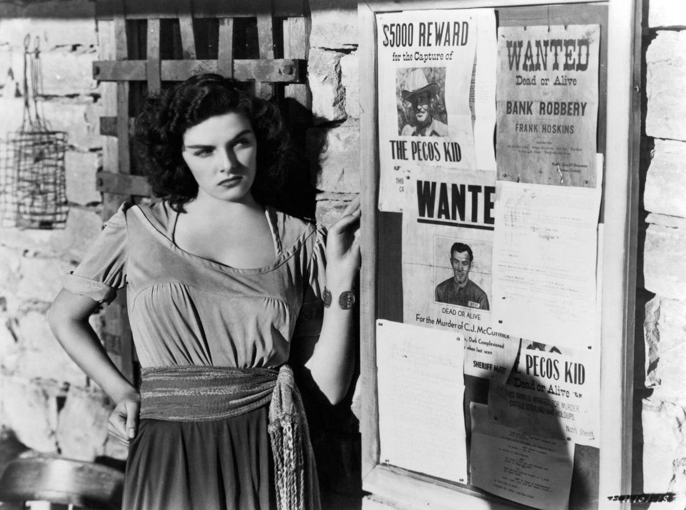Jane Russell looking at 'Wanted' posters in a scene from the film 'The Outlaw', 1943.