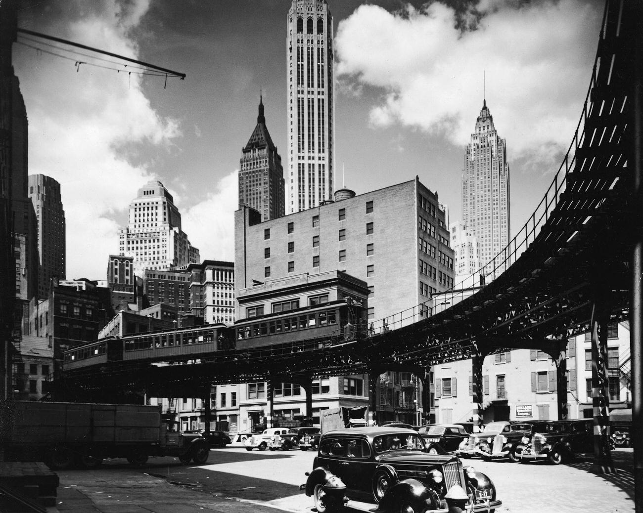 Skyline view of Manhattan's financial district that shows an elevated train line and, at the right, 1930s