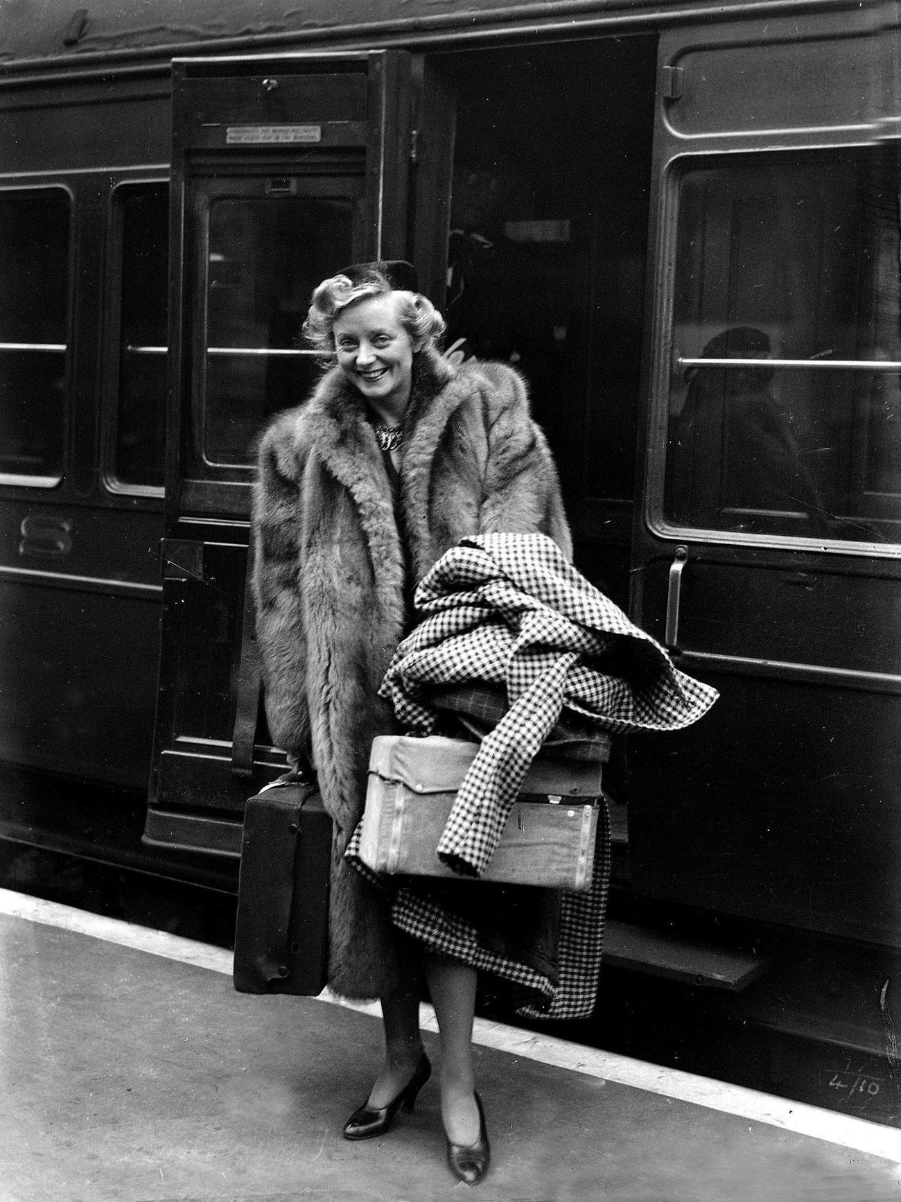 British musical comedy actress Evelyn Laye is pictured arriving by train, 1938