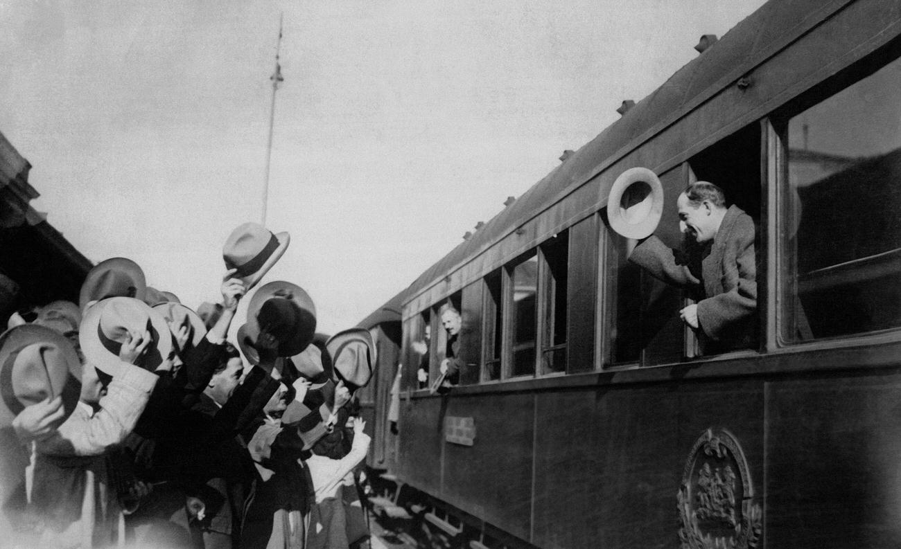 King Boris III of Bulgaria raises his hat to greet the crowd who came to wish him a good trip when he left by train to visit his fiancée in Italy on October 16, 1930