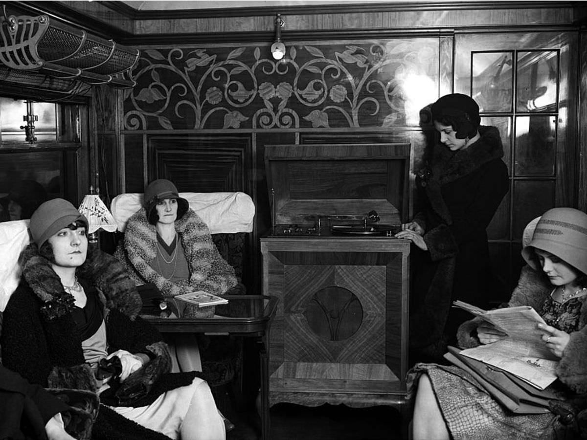 Passengers listen to a radio gramophone on a LNER train carriage in 1930.