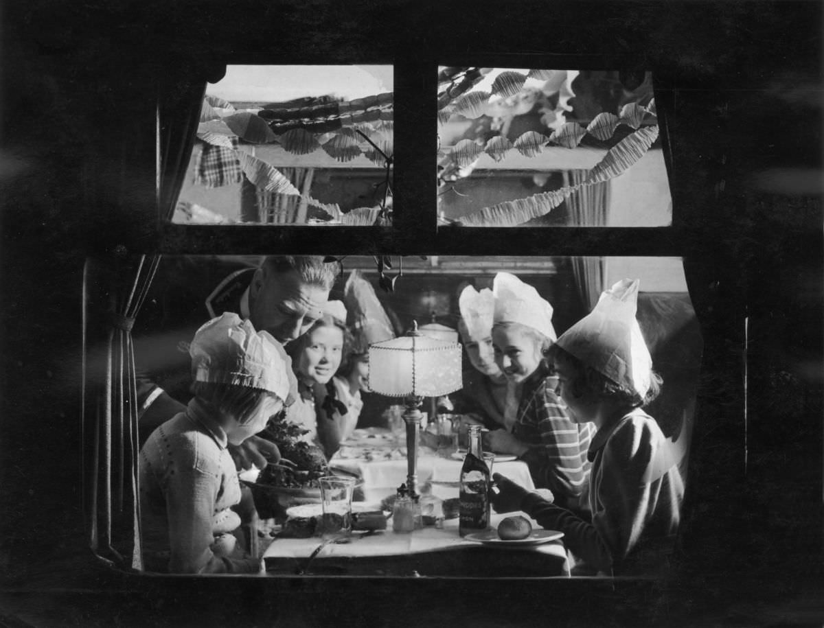 Children enjoying a festive party in an LMS dining car while traveling home for Christmas, 1938.