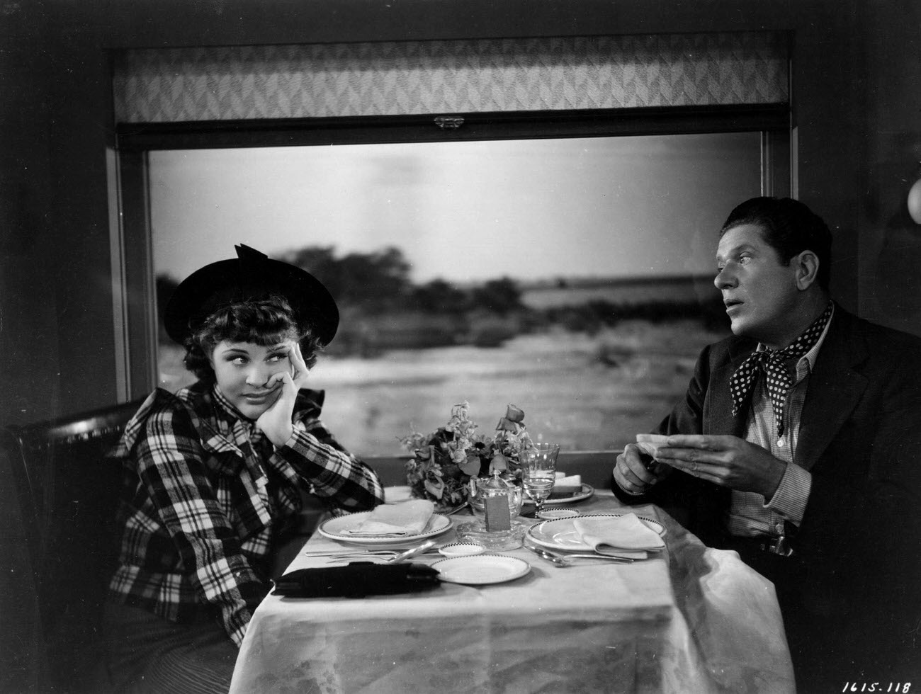 American comedian Bob Burns shares a meal with comedienne and vocalist Martha Raye in the dining car of a train