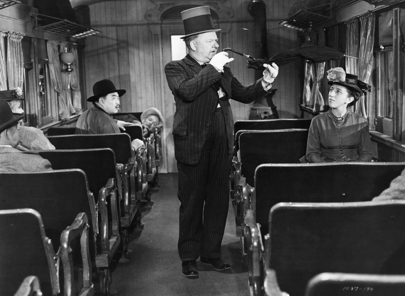 Margaret Hamilton bent umbrella in a scene from the film 'My Little Chickadee', in train