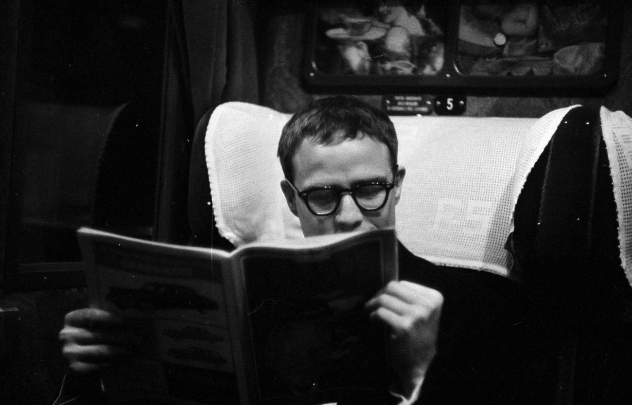 Marlon Brando sitting in a train, reading a magazine, 1954