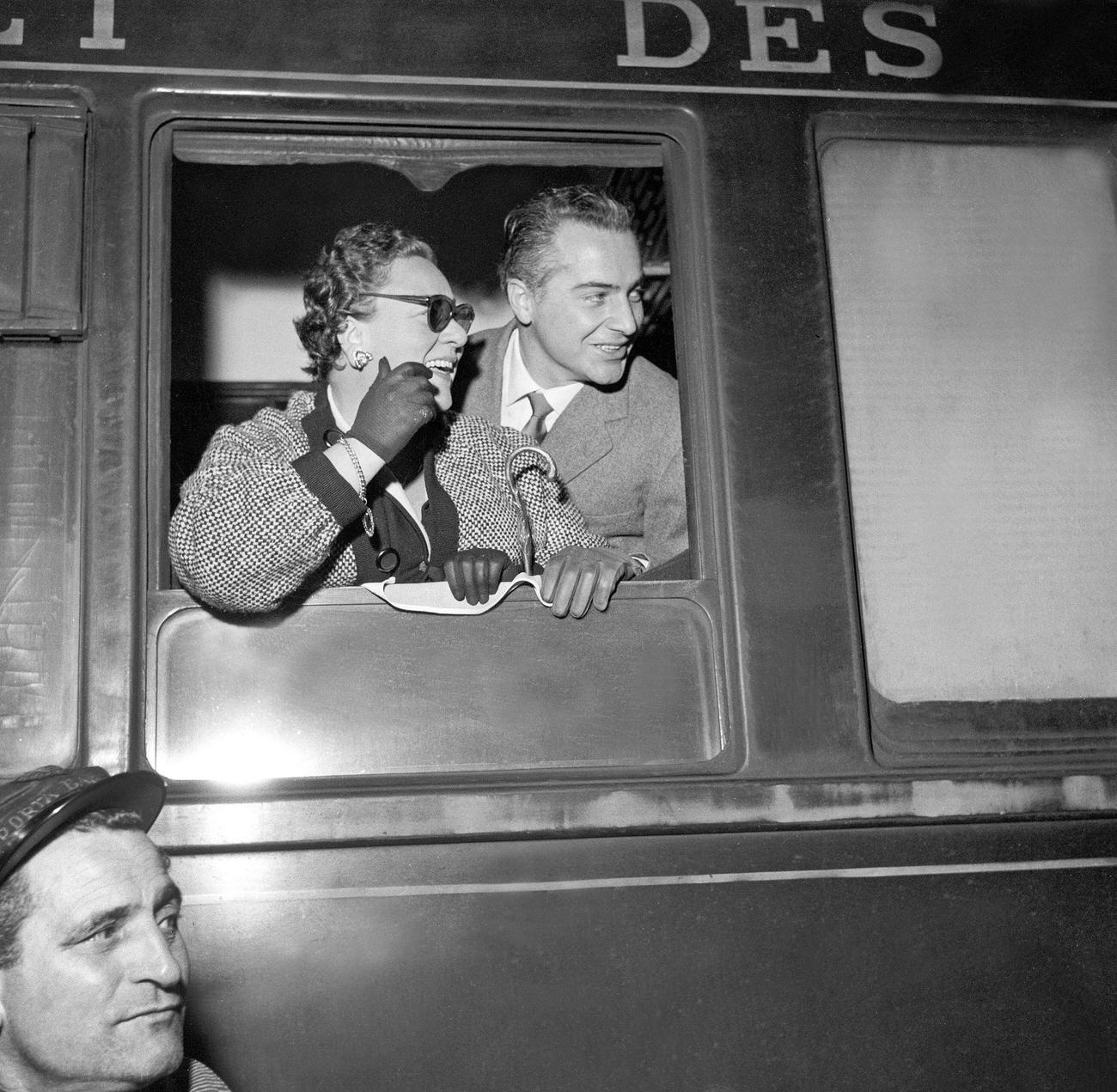 Italian actor Rossano Brazzi and his wife Lidia Bertolini appearing at their train window while coming back from Paris at Termini railway station. Rome, December 1955
