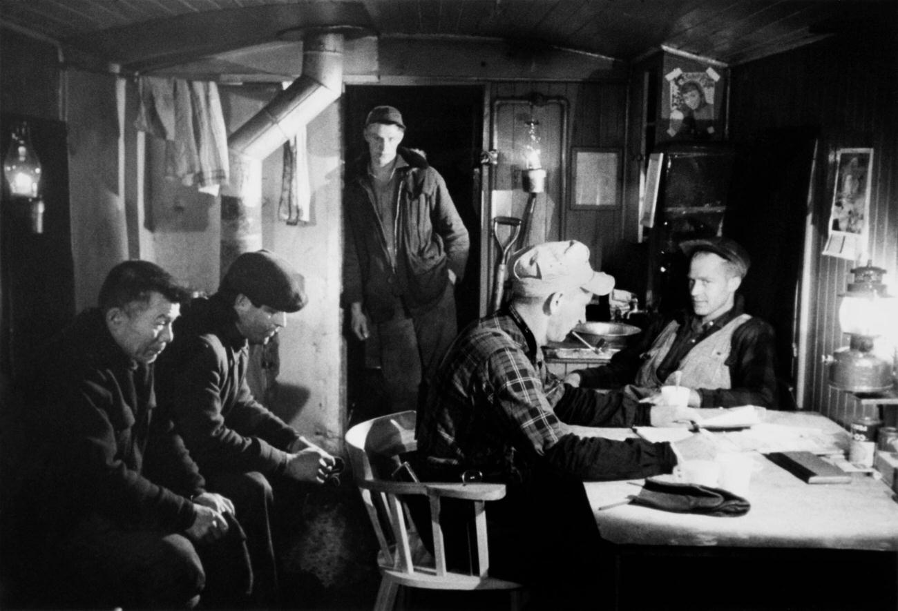 Railway workers inside a railcar on their way to work near Glacier, a railway whistlestop and locality near the summit of the Rogers Pass in Glacier National Park, British Columbia, Canada, 1958.