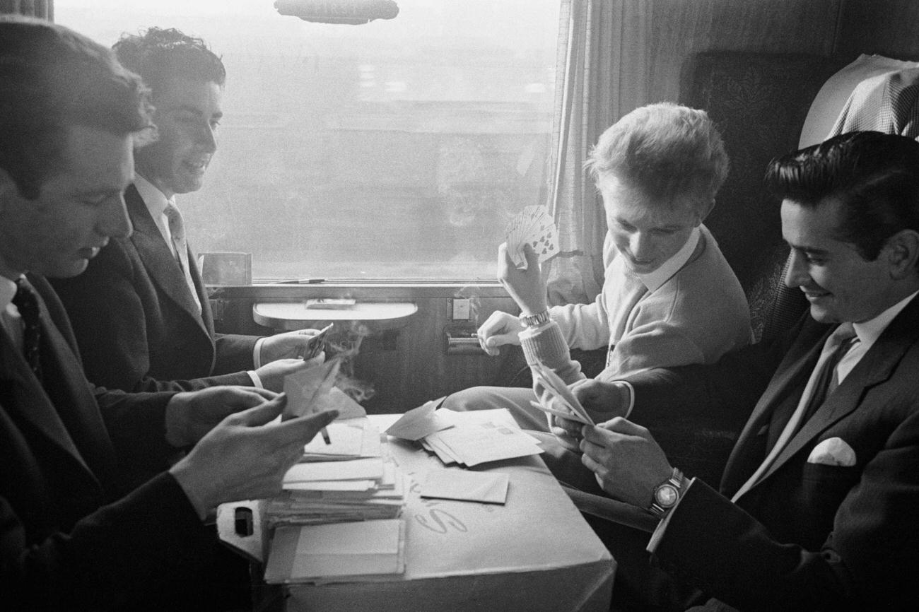 English pop idol Tommy Steele takes a train journey with his managers Larry Parnes (left, window seat) and John Kennedy (right, aisle seat), 4th March 1957.
