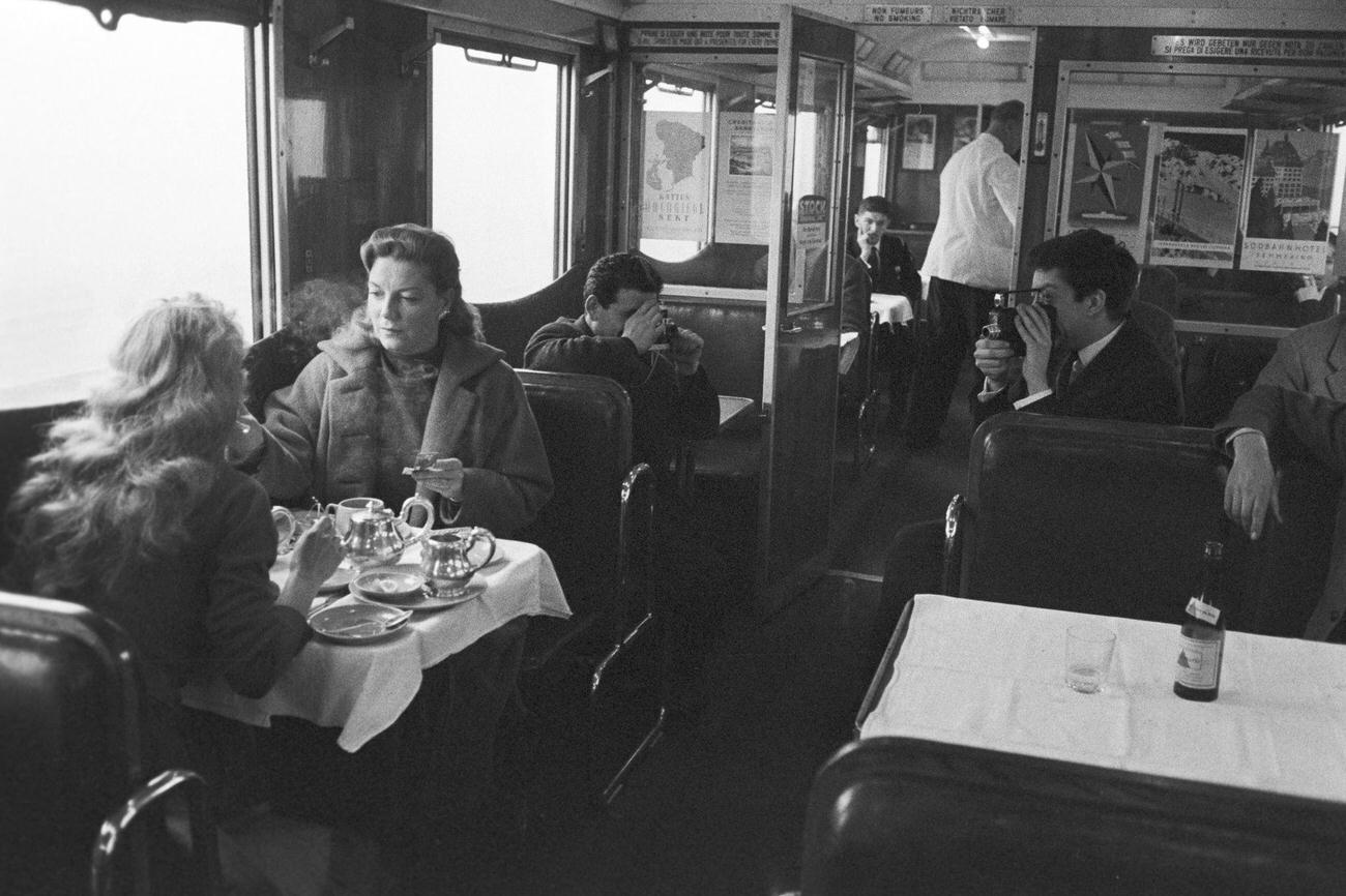 Brigitte Bardot during a breakfast chat with a woman in the train, 1957