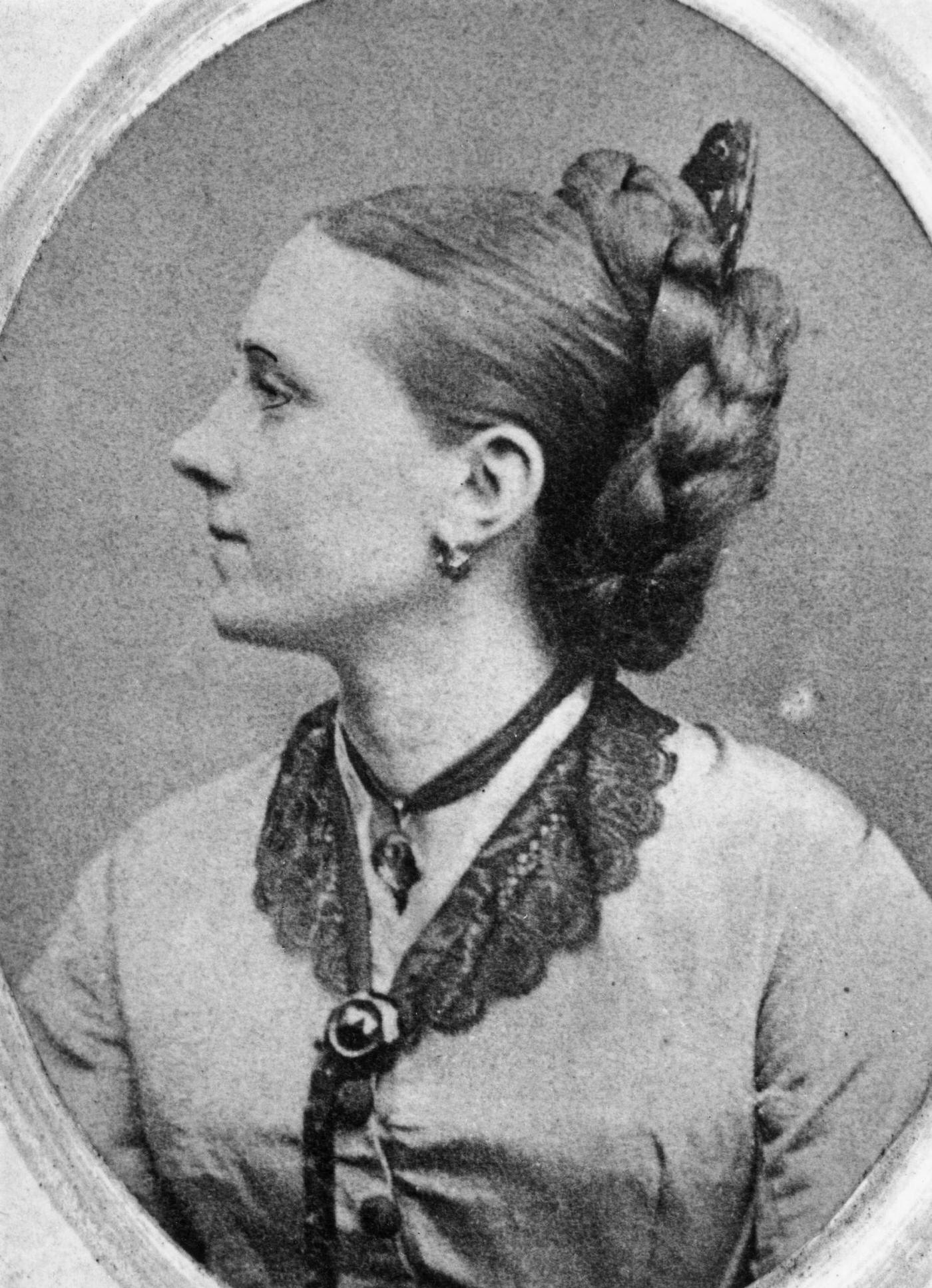 A woman with her long hair braided and coiled behind her head, 1870.