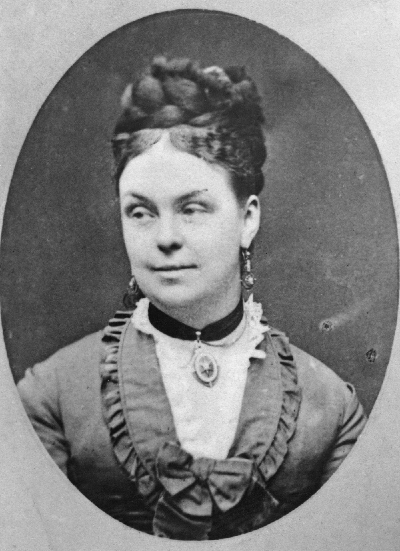 A woman with her hair braided and piled on top of her head, 1870