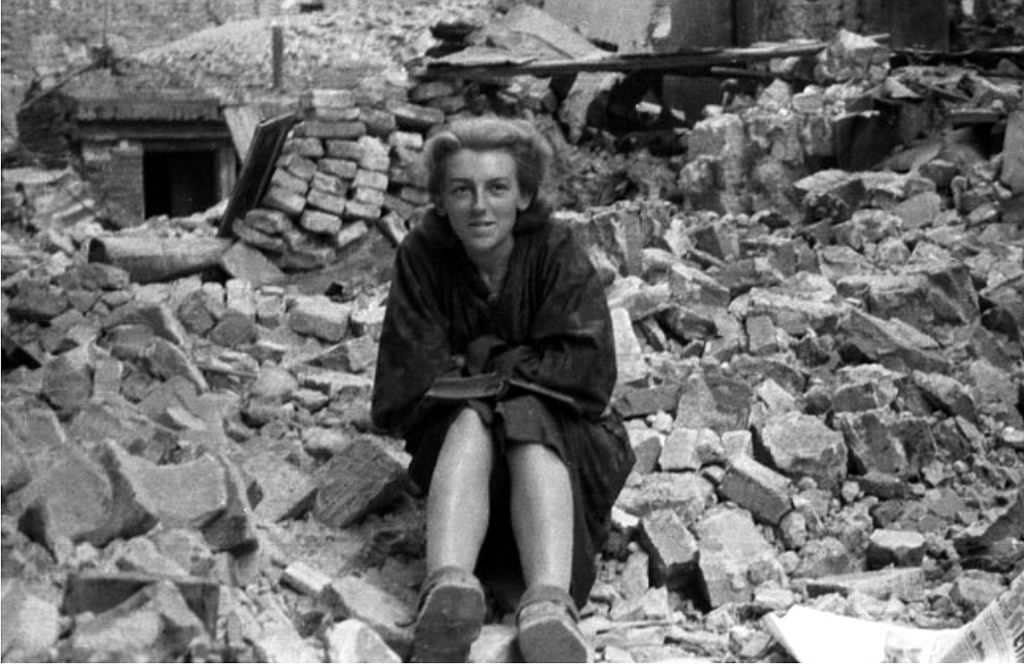 Girl from Anna Company of the Gustaw battalion reading a book amid the rubble on Ślepa Street in the Old Town.