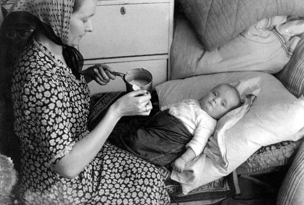 A mother feeding her young daughter in a building on Sienna Street.