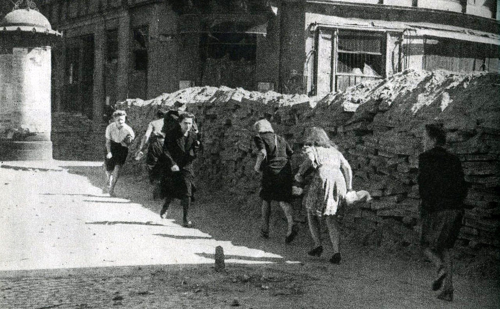 People crossing Wielka Street behind a barricade under fire from Germans.