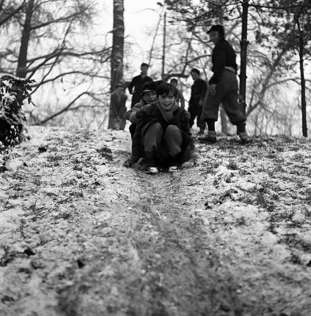 Children playing on a slope covered with snow in a park after a snowfall, Milan, 1950s. (Mario De Biasi)