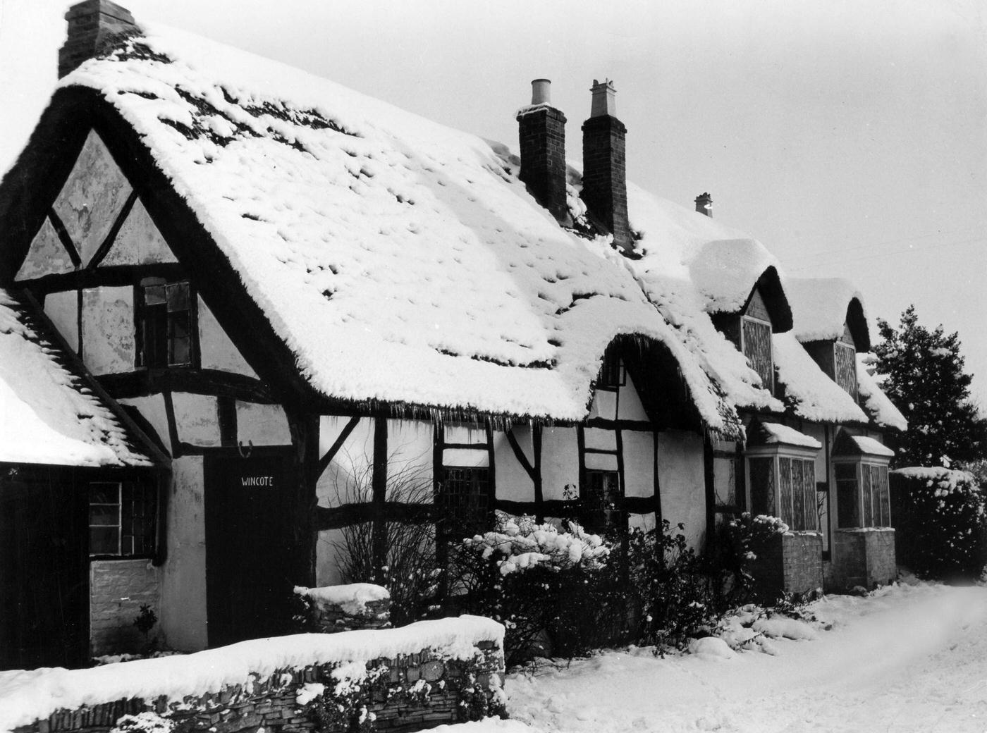 England. A wintry scene at Welford with snow and icicles hanging from a thatched roof cottage.