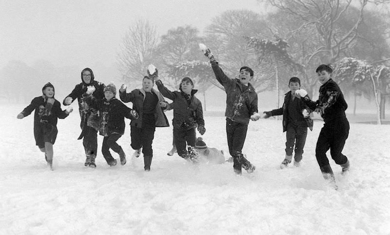 Children on holiday from school throwing snowballs on Tooting Bec Common, 1962.