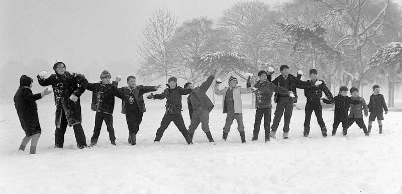 Children on holiday from school throwing snowballs on Tooting Bec Common, 1962.