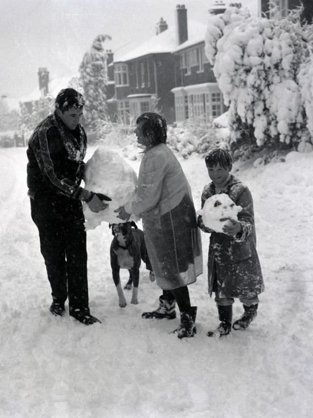 Children build a snowman with the help of their boxer dog in Hadley Wood, Hertfordshire, 1962. (George Greenwell)