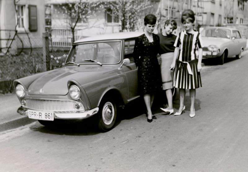 Three stylish ladies posing with a DKW Junior in a residential street. The car is registered in the West German town of Springe, 1962