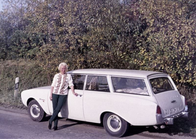 A platinum-blonde lady posing with a Ford Taunus 17M Turnier on a sunny autumn's day. The car is registered in the West German town of Oldenburg, 1965